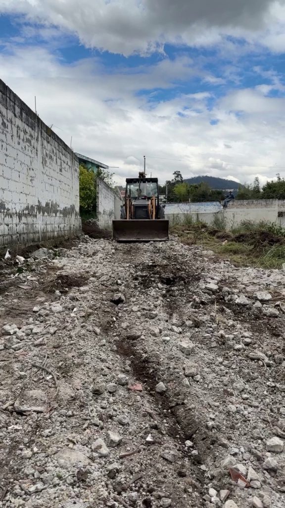 Retroexcavadora realizando limpieza y movimiento de tierras para terrenos Conocoto residencial inversión.