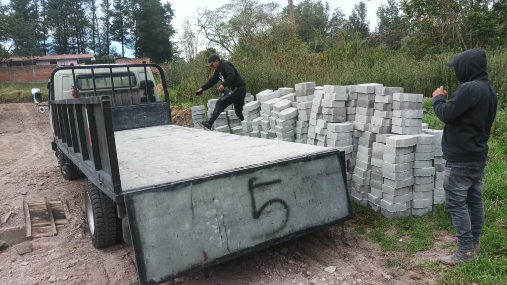 Obrero descargando adoquines, como parte del suministro de materiales para el proyecto terminado Jardines Ushimana.
