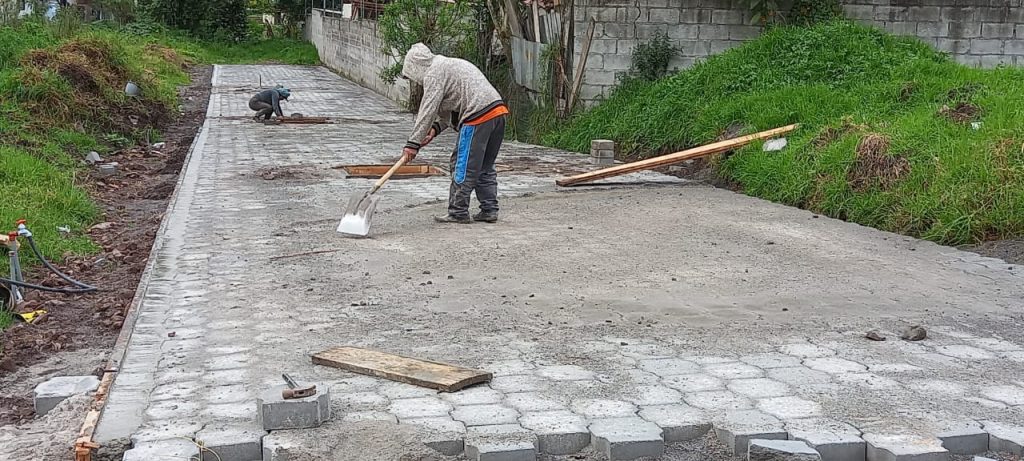 Obrero colocando adoquines en la fase de finalización de infraestructura del proyecto terminado Jardines Ushimana.